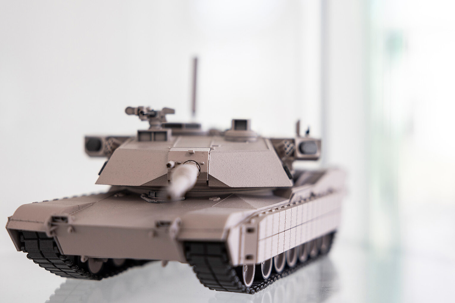 Nahaufnahme eines Modellpanzers in mattem Grau, aufgenommen von vorne mit Fokus auf den Kanonenlauf und die Kettenglieder.
