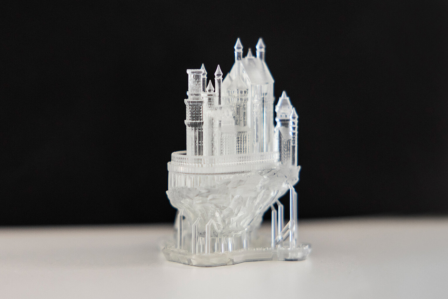 Miniaturmodell einer transparenten Burg auf einem Felsen vor schwarzem Hintergrund