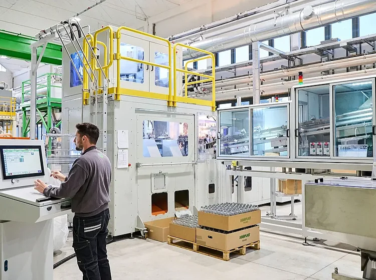 Ein Mitarbeiter bedient das Steuerpult einer Serioplast Industriemaschine in einer Fertigungshalle   